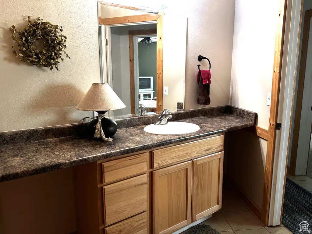Bathroom with a textured wall, vanity, and light tile patterned floors