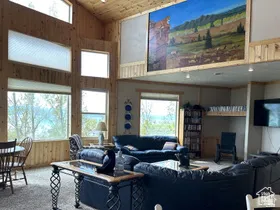 Living area with wooden walls, a vaulted wood ceiling, plenty of natural light, and carpet