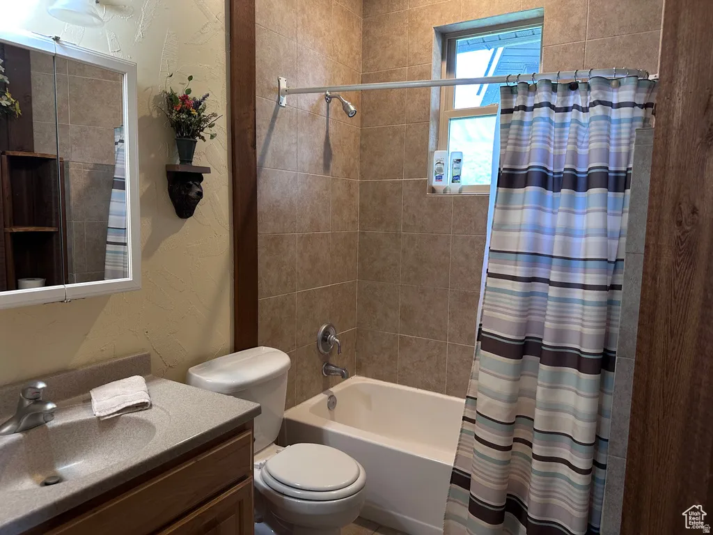 Full bath with a textured wall, vanity, and shower / bath combo with shower curtain