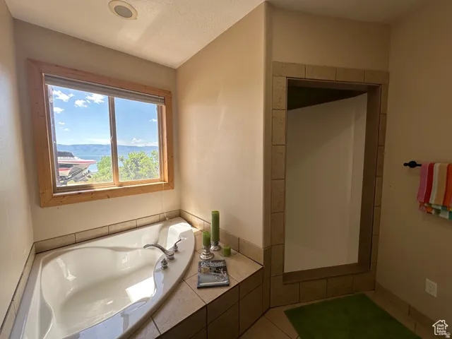 Full bathroom featuring a garden tub, a textured ceiling, a shower stall, and a mountain view