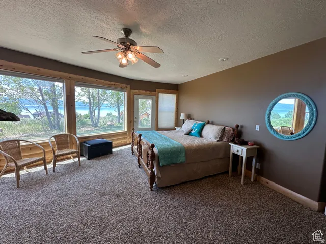 Carpeted bedroom with access to exterior, a textured ceiling, and ceiling fan