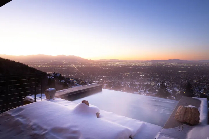 Infinity hot tub at dusk featuring  mountain and city views