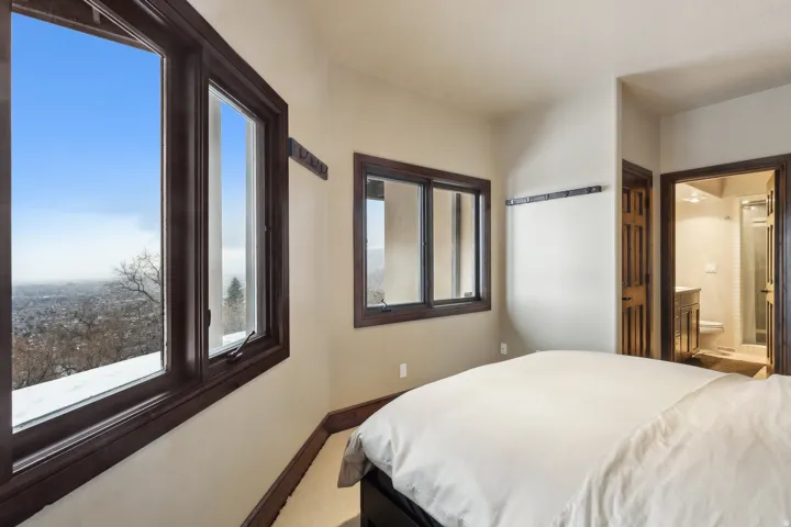 Bedroom with ensuite bathroom, multiple windows, and carpet
