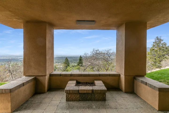 Covered outdoor patio with stone paver flooring and an integrated fire pit