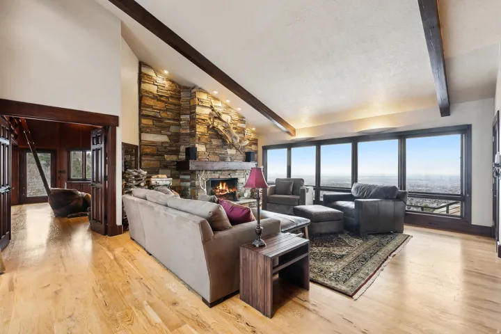 Living area with a custom wood burning fireplace, oak flooring, & vaulted ceiling.