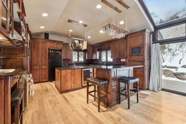 Kitchen features a center island, vaulted ceiling, 2 free standing refrigerators, a commercial ice maker, a wine frig, & recessed dimmable lighting.