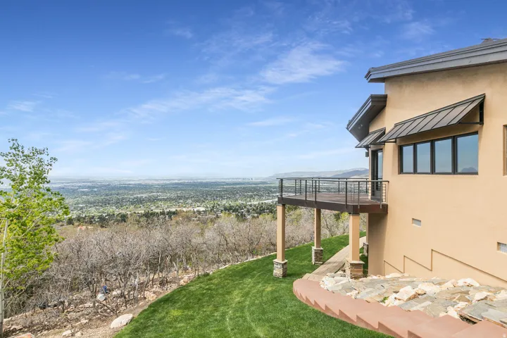 Exterior featuring a balcony with metal railings and wood-finish decking, awnings over windows, and a stucco finish