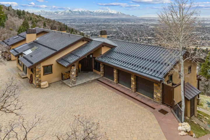 View of front of house with a chimney, stone siding, stucco siding, decorative driveway, and a mountain view