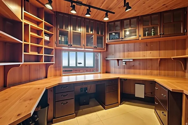 Custom cherry wood cockpit style office with integrated desk, filing cabinets, and window for sunset views.