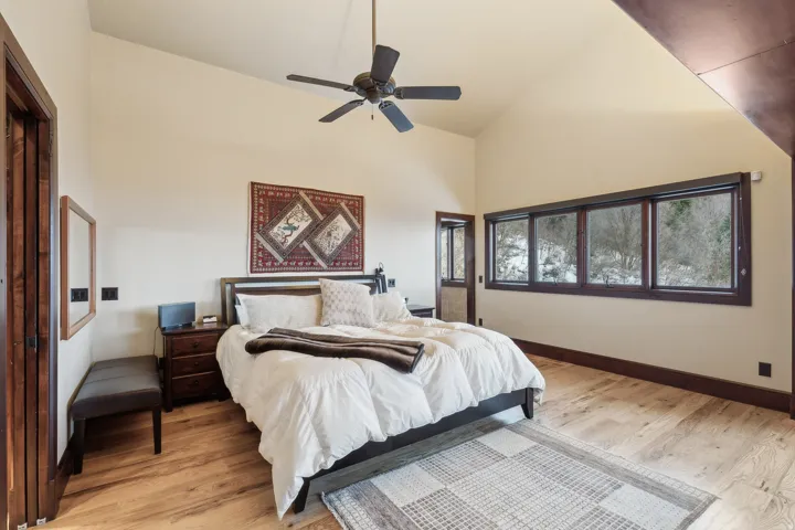 Primary suite bedroom featuring light wood-style flooring, ceiling fan, and vaulted ceiling