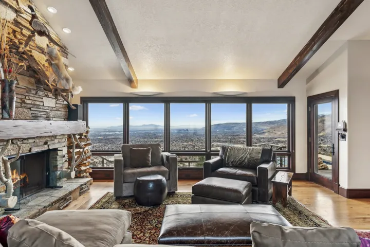 Living area featuring beam ceiling, wood finished floors, a mountain view, and a stone fireplace