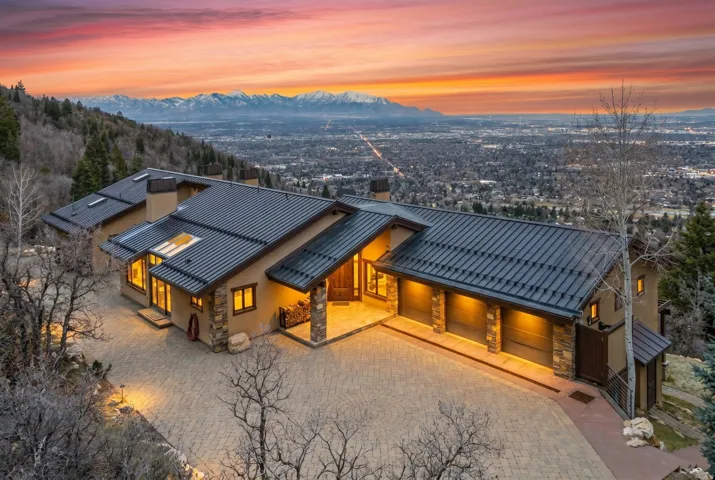 Rear view of house with a chimney, stone siding, a mountain view, decorative driveway, and a standing seam roof