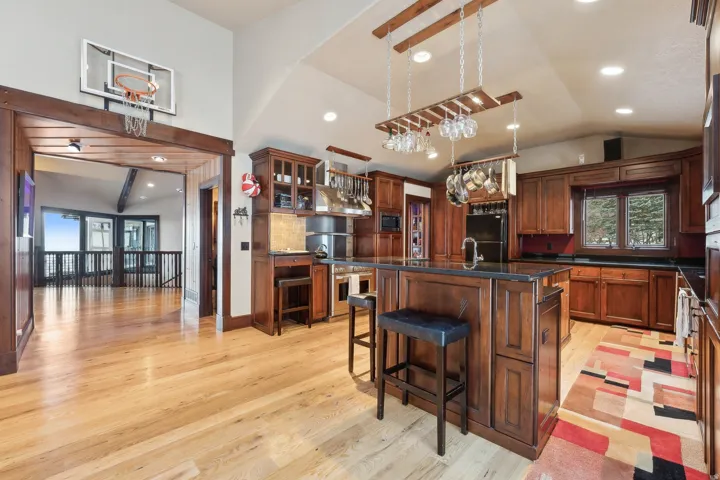 Kitchen featuring an island with sink, lofted ceiling, glass insert cabinets, a kitchen bar, and light wood finished floors