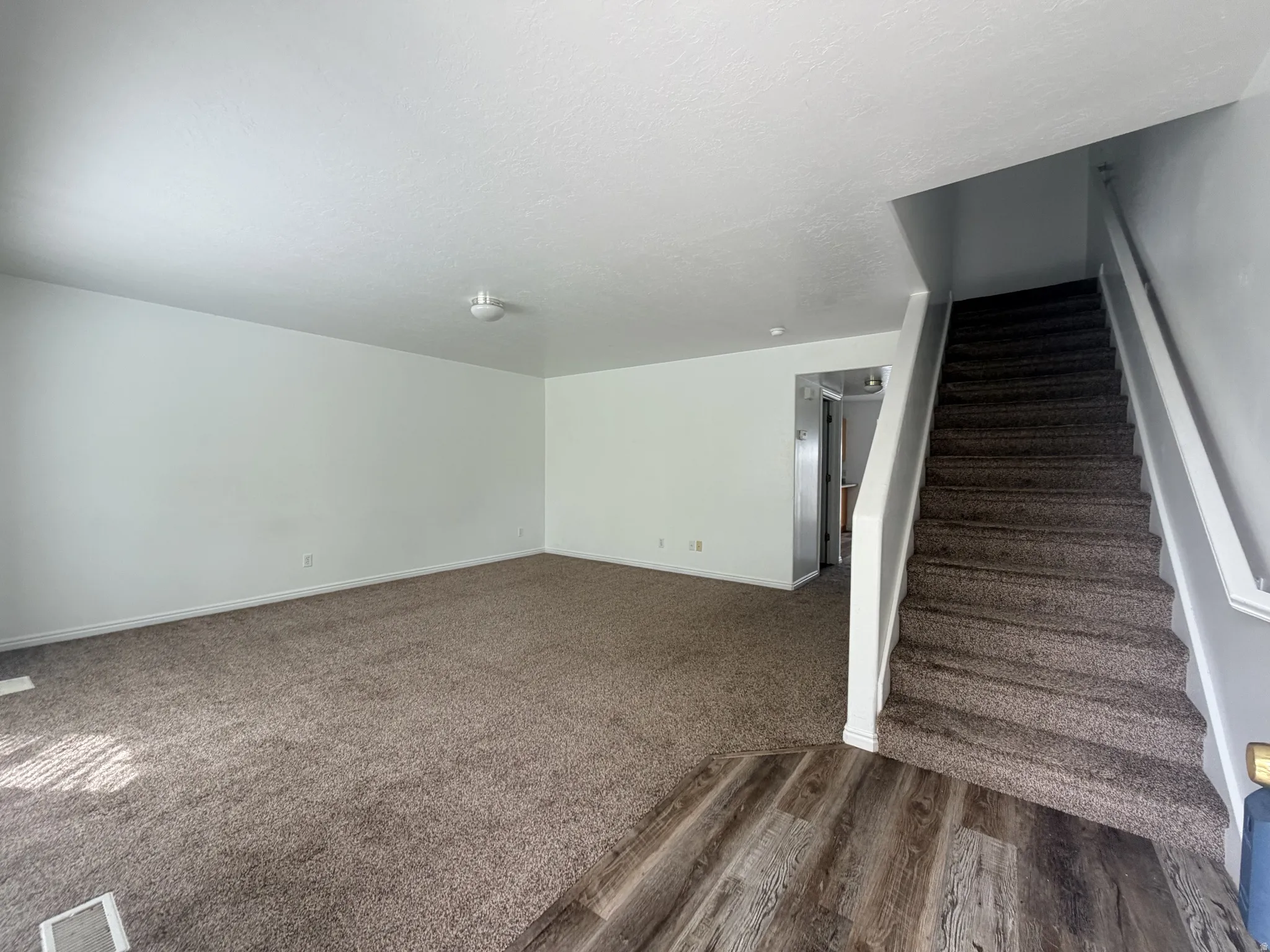 Stairway featuring a textured ceiling and wood finished floors