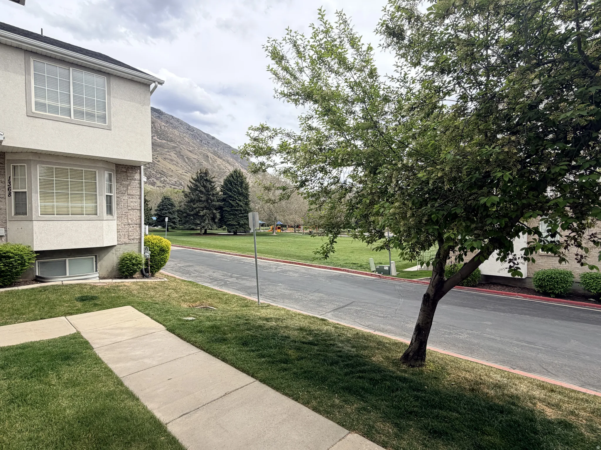 View of asphalt road featuring curbs, a mountain view, and sidewalks
