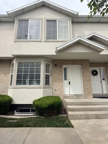 View of front of property featuring stucco siding, brick siding, and a porch