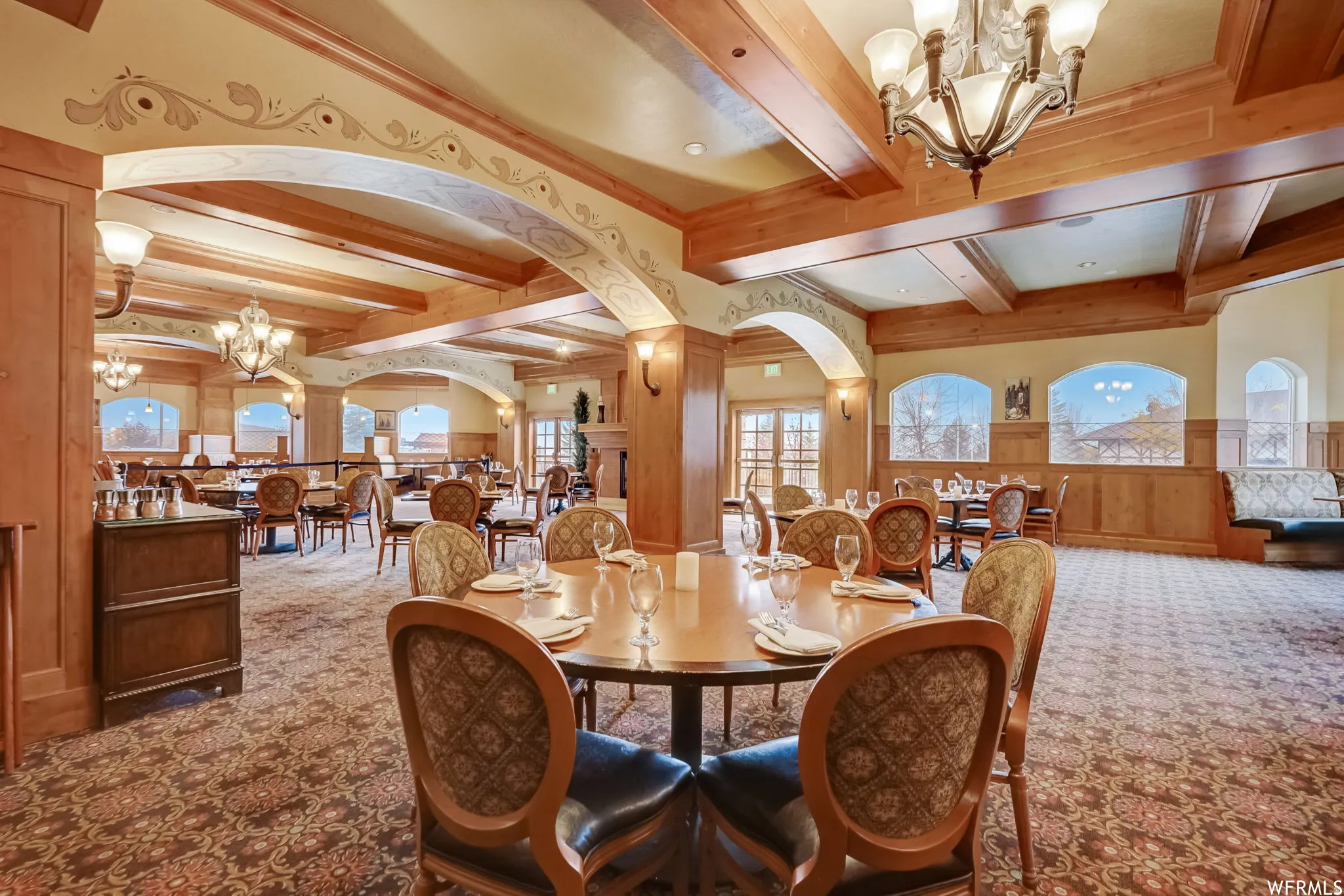 Dining area featuring hanging lights, carpet, wood walls, beam ceiling, and arched walkways