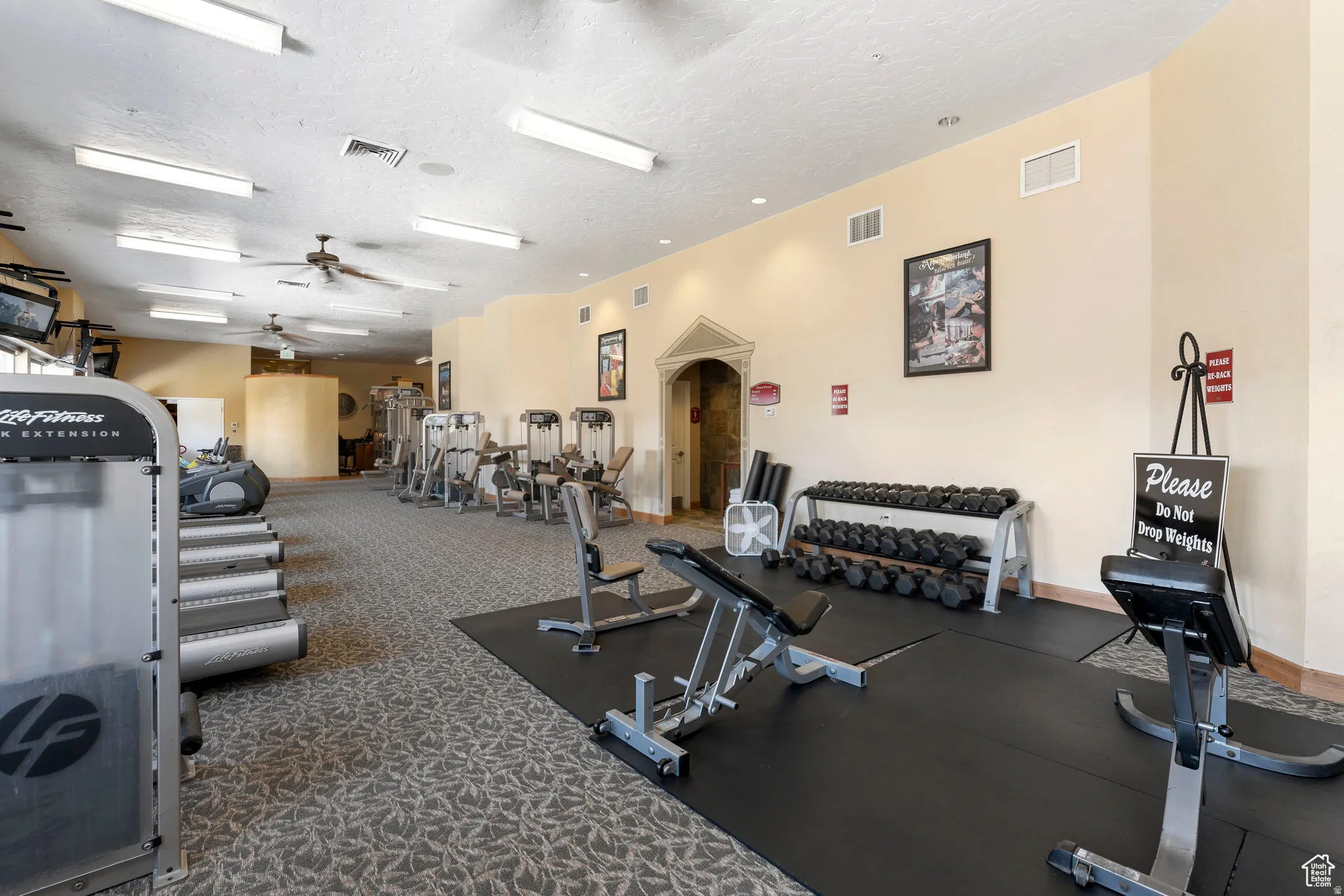 Gym with ceiling fan and a textured ceiling