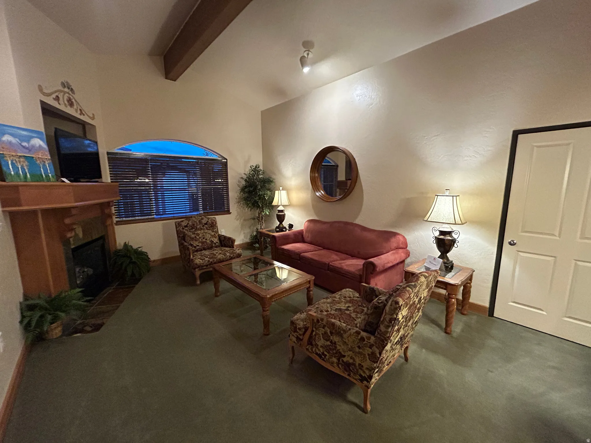 Living room featuring a fireplace, carpet, and vaulted ceiling with beams