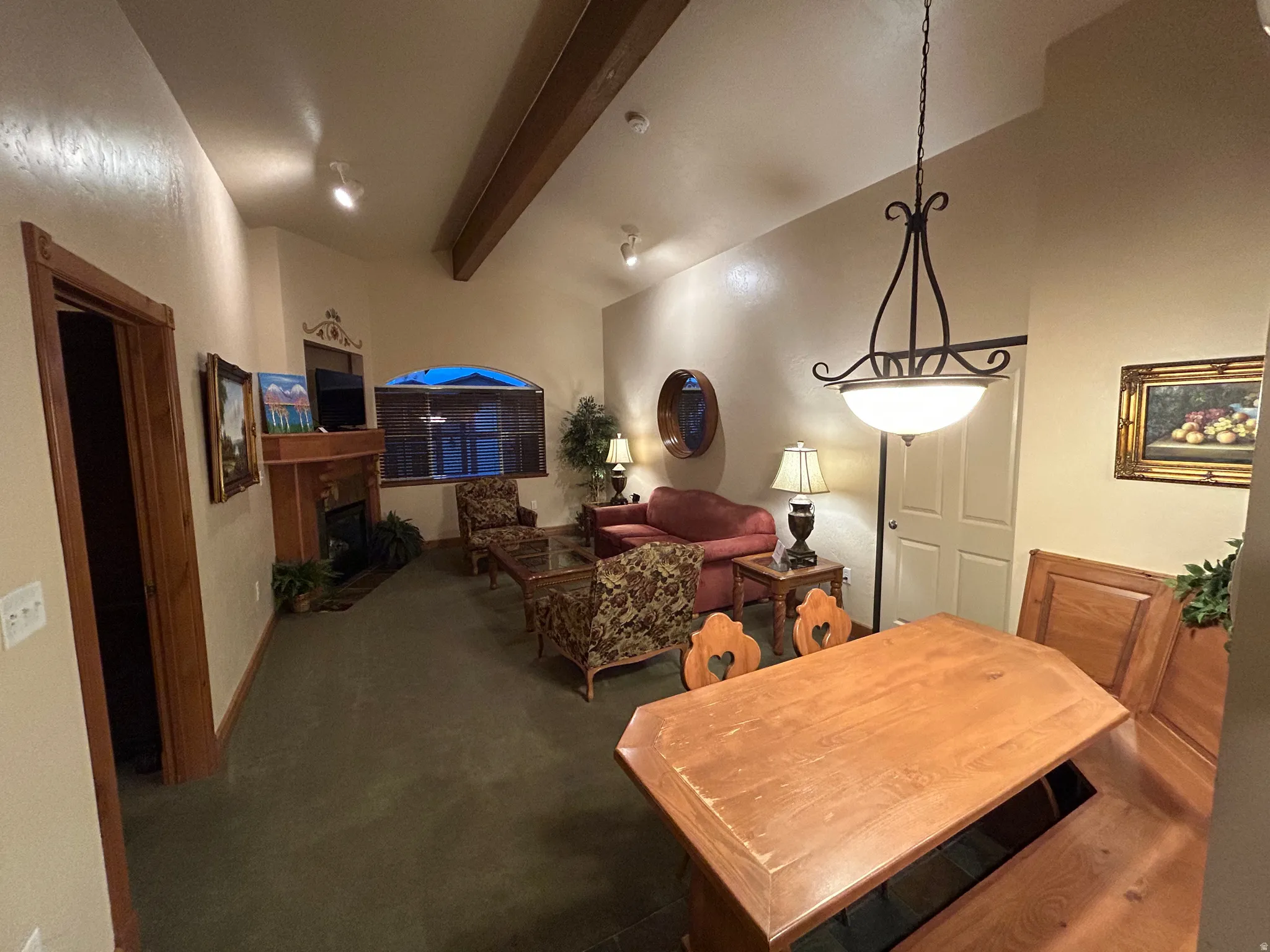 Carpeted dining room featuring a fireplace and vaulted ceiling with beams