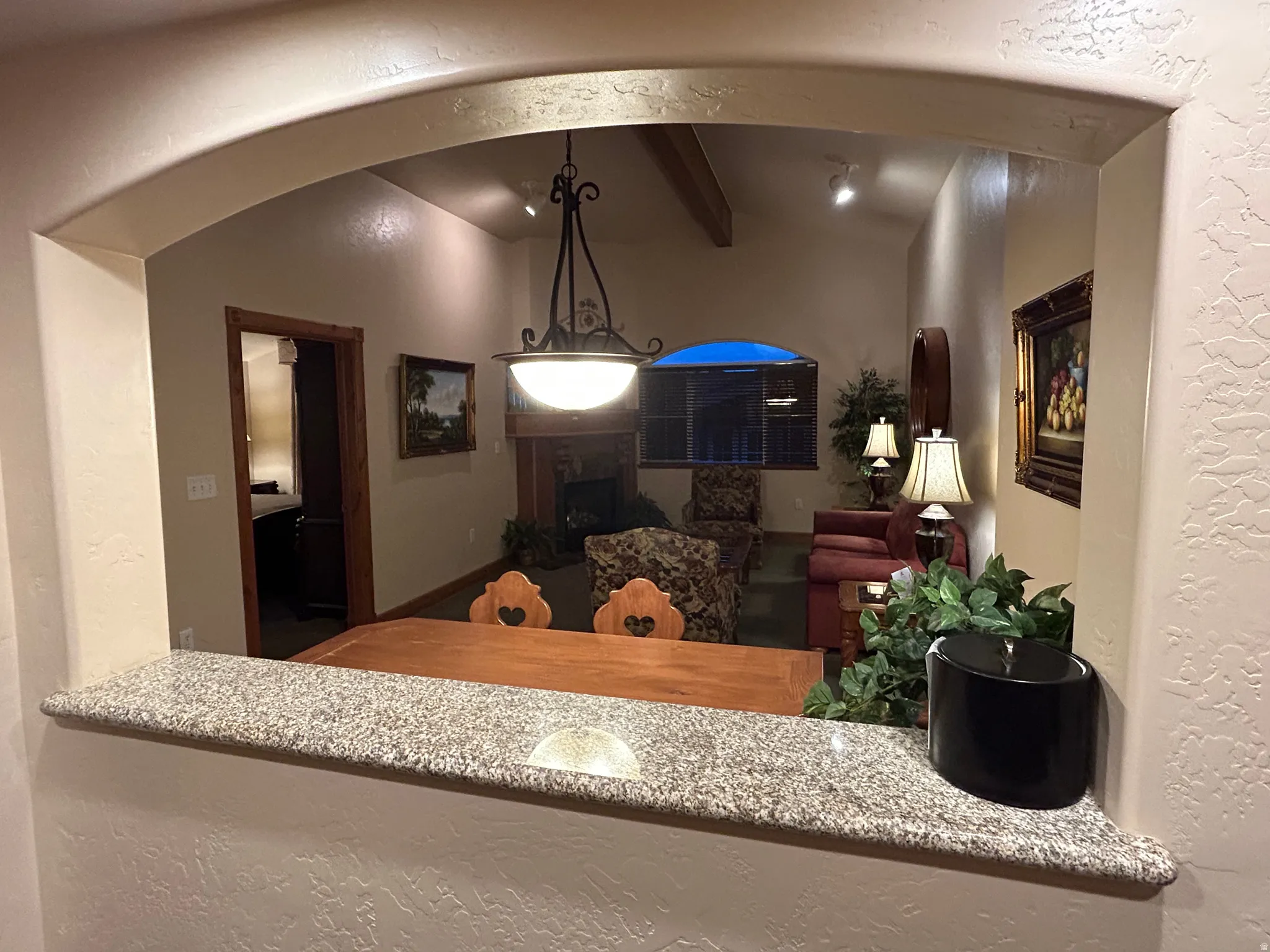 Kitchen featuring a textured wall, vaulted ceiling with beams, and hanging light fixtures