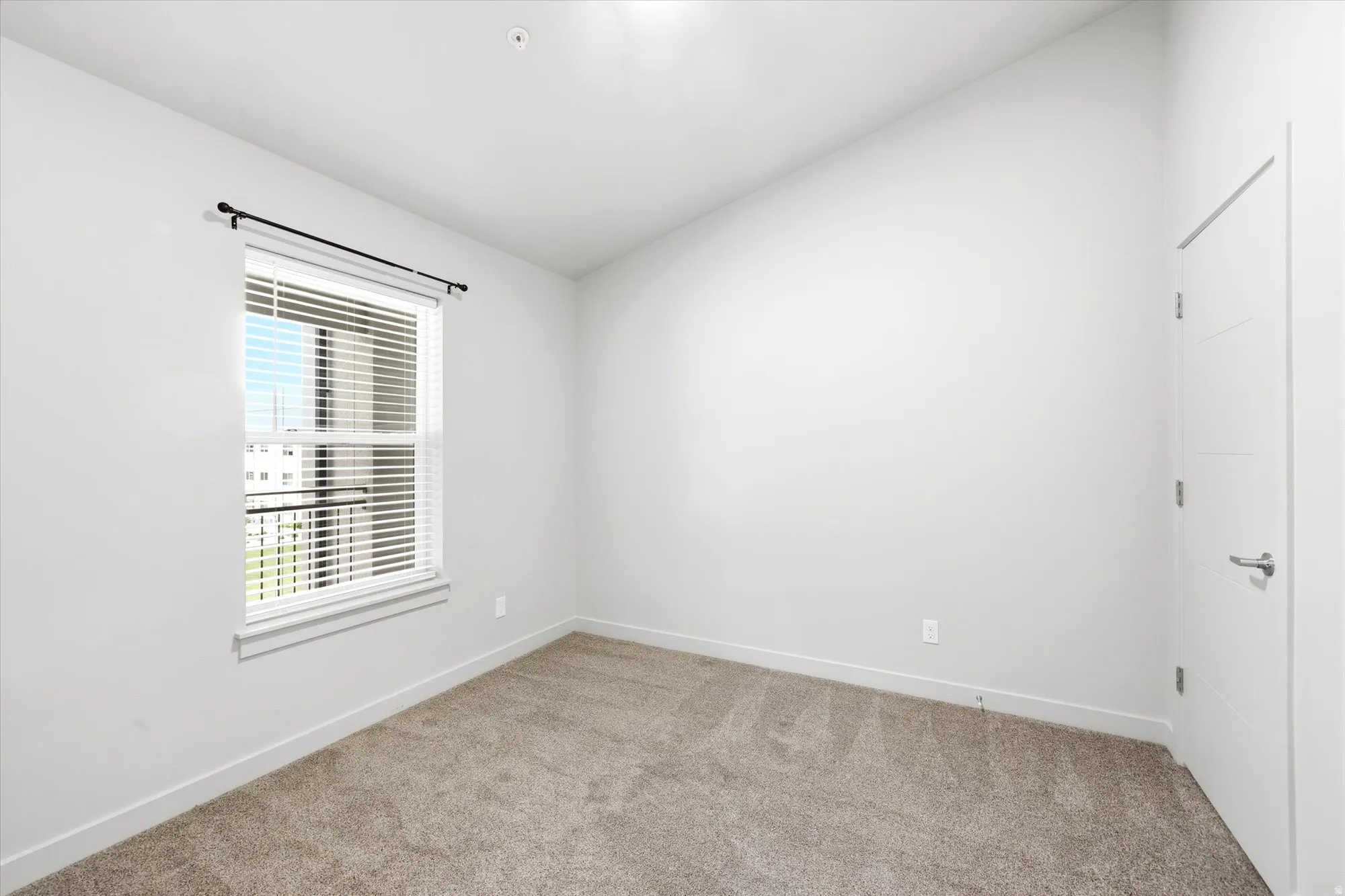 Empty room featuring lofted ceiling and light colored carpet