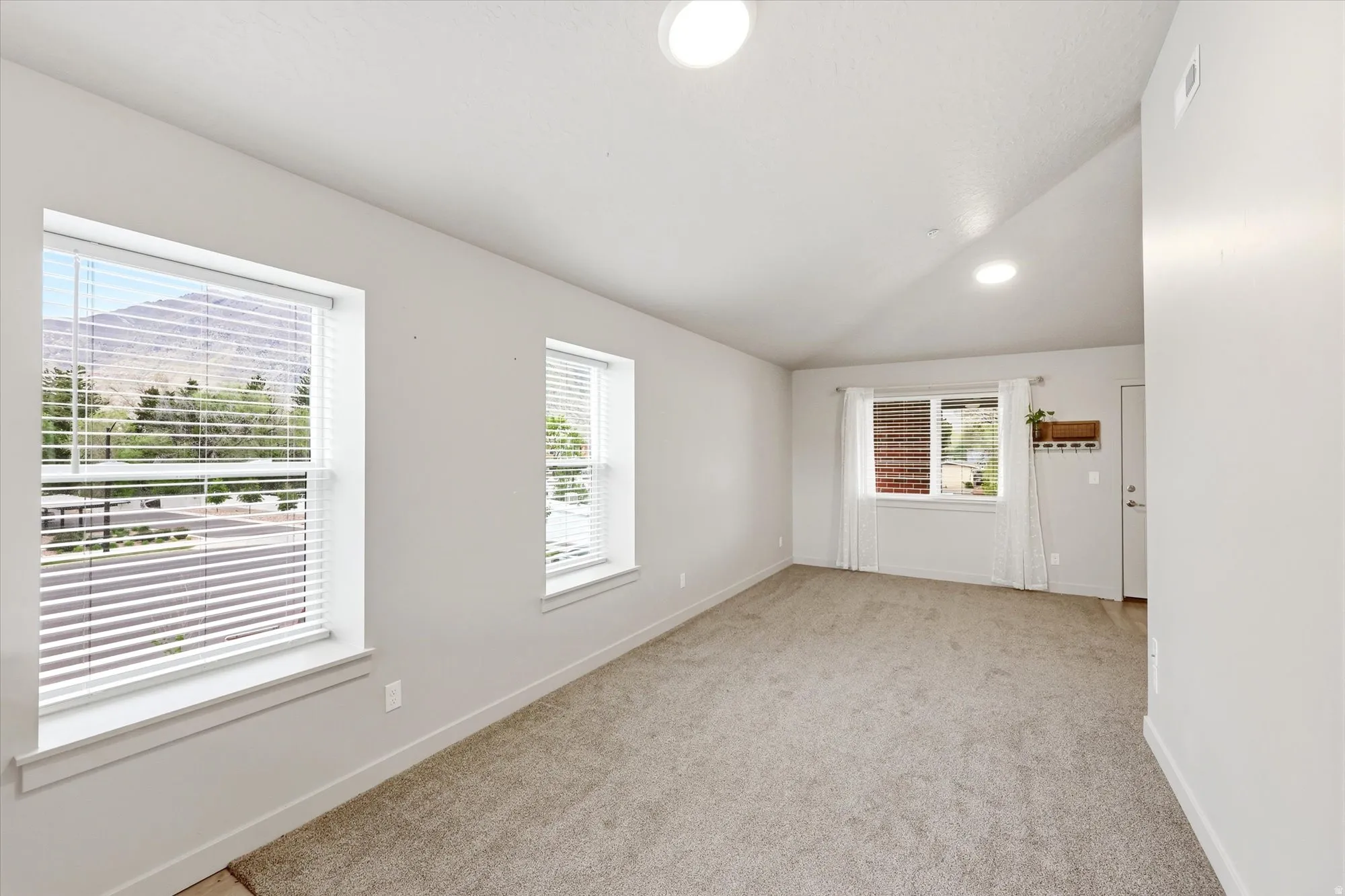 Unfurnished room featuring lofted ceiling and light carpet