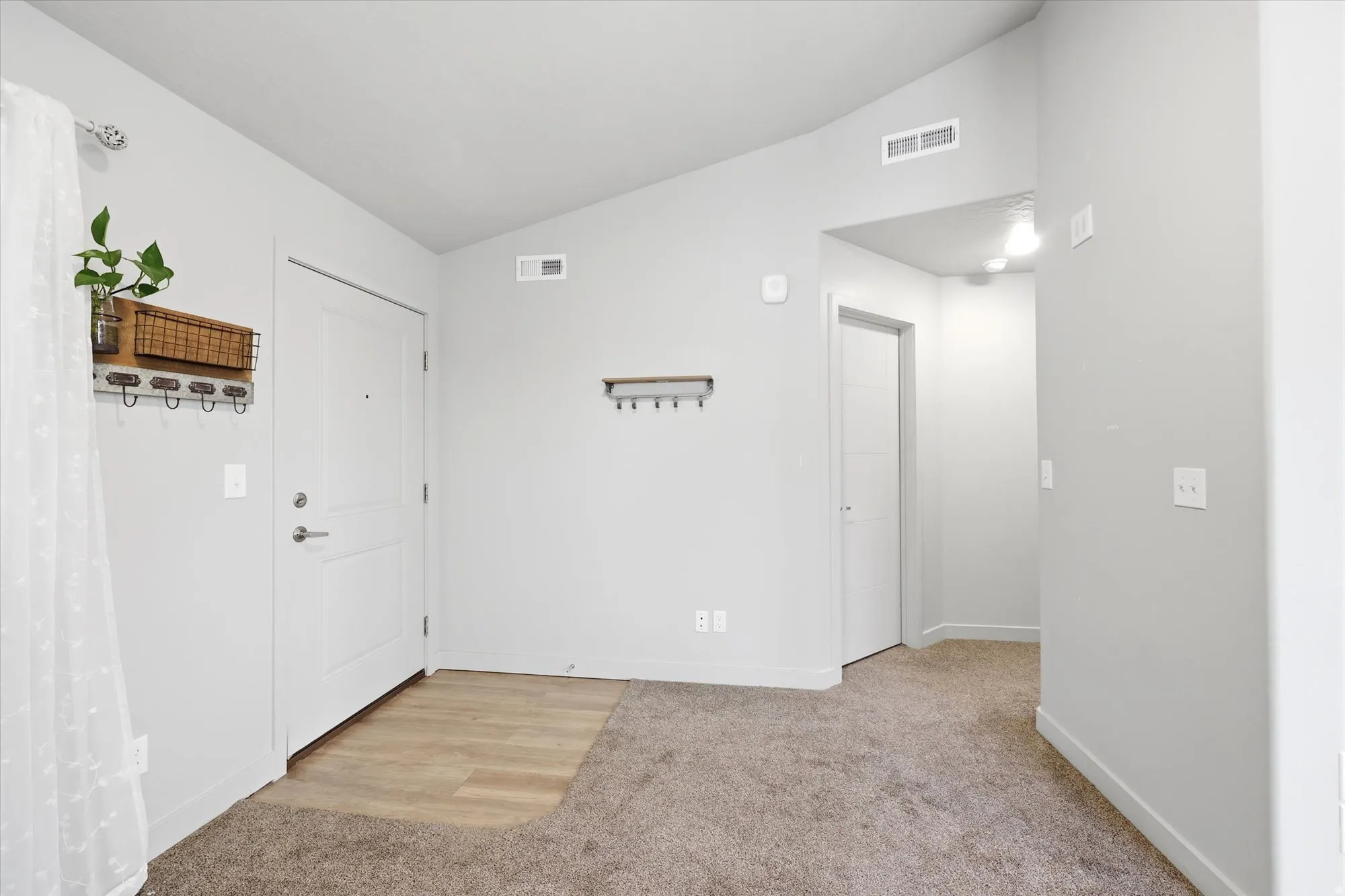 Foyer with lofted ceiling and light carpet