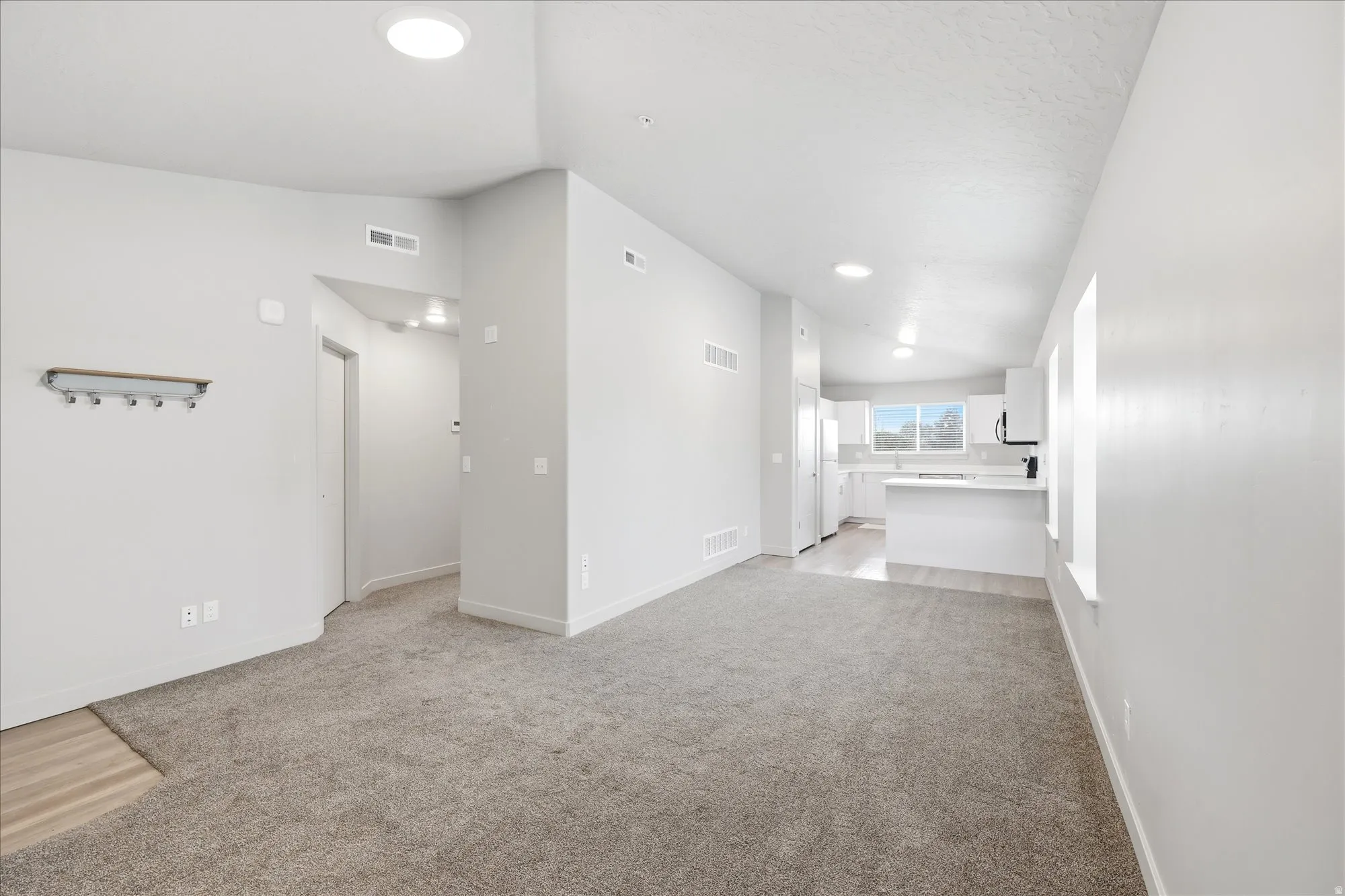 Spare room featuring vaulted ceiling and light carpet