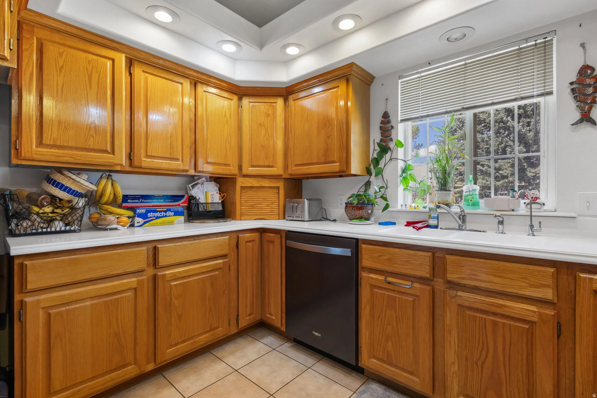 Kitchen featuring recessed lighting, light countertops, wood finish cabinetry, dishwashing machine, and light tile patterned floors
