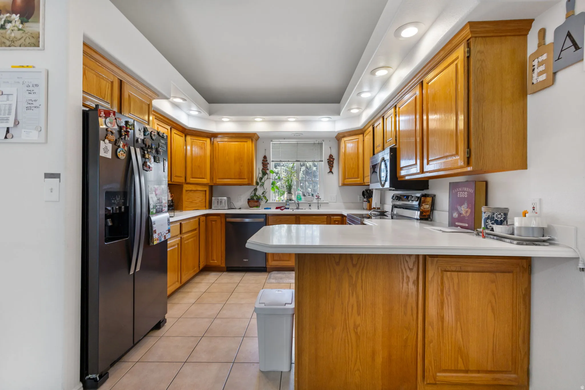Kitchen featuring wood finish cabinetry, a peninsula, light countertops, recessed lighting, and stainless steel appliances