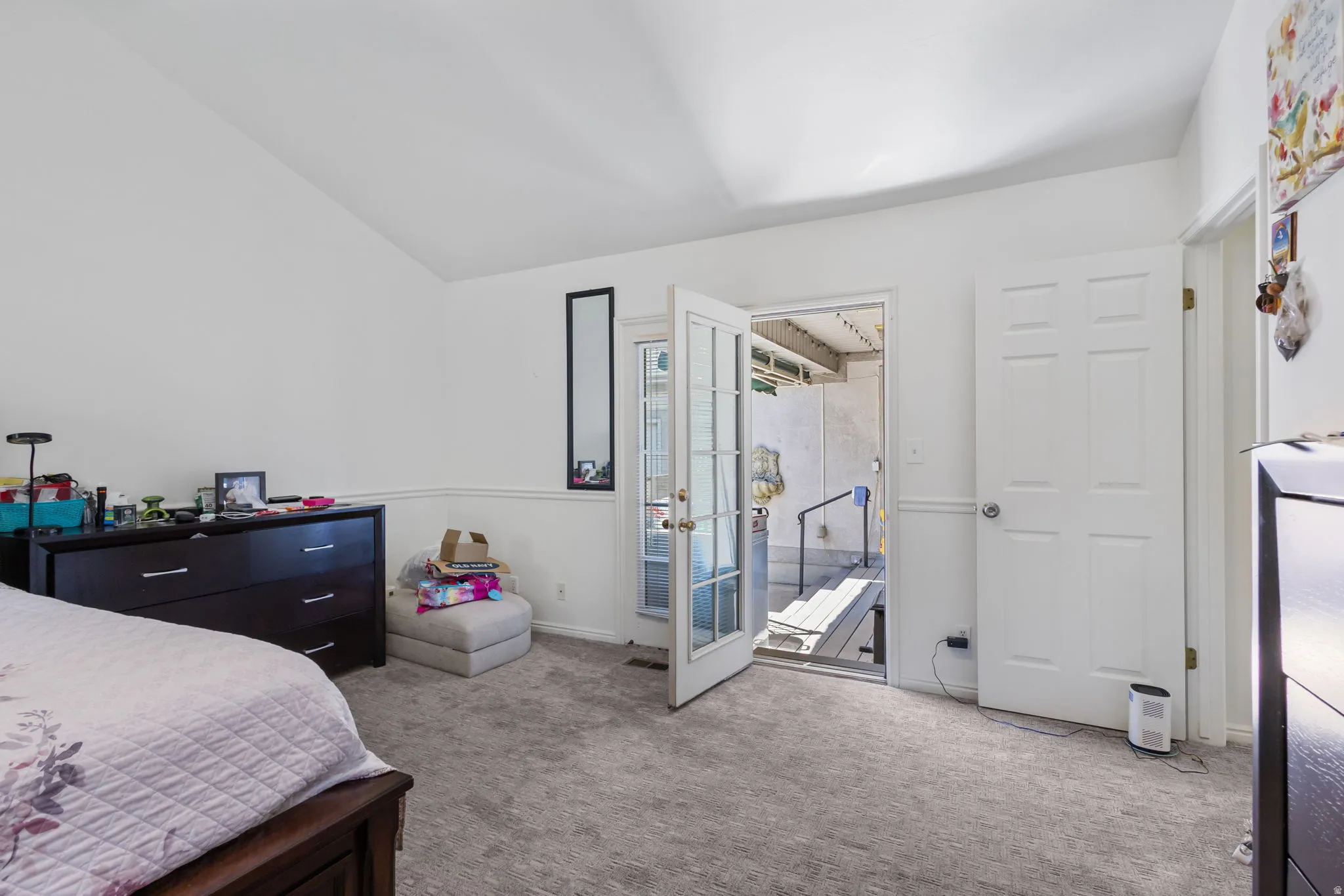 Bedroom with lofted ceiling, light carpet, and access to outside
