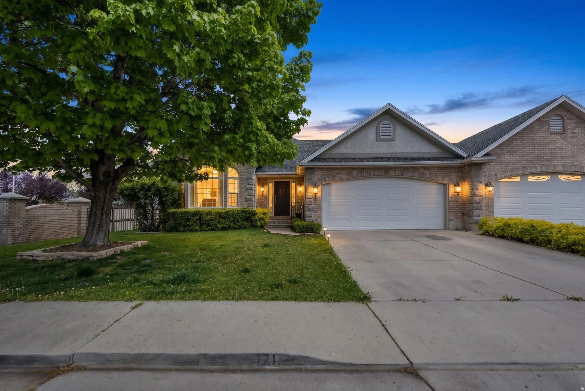 View of front of property with an attached garage, a front lawn, driveway, roof with shingles, and brick siding