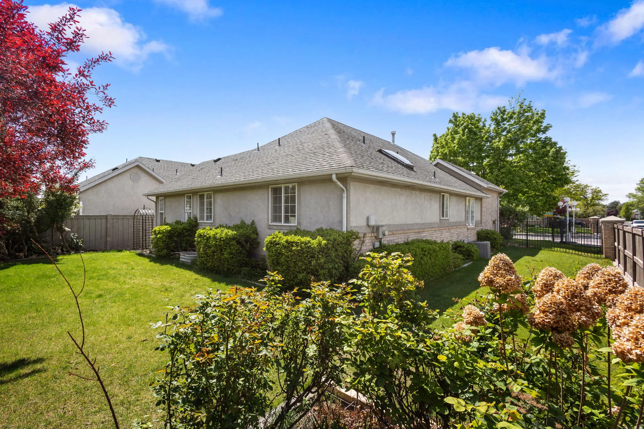 View of side of home with a fenced backyard, stucco siding, and roof with shingles