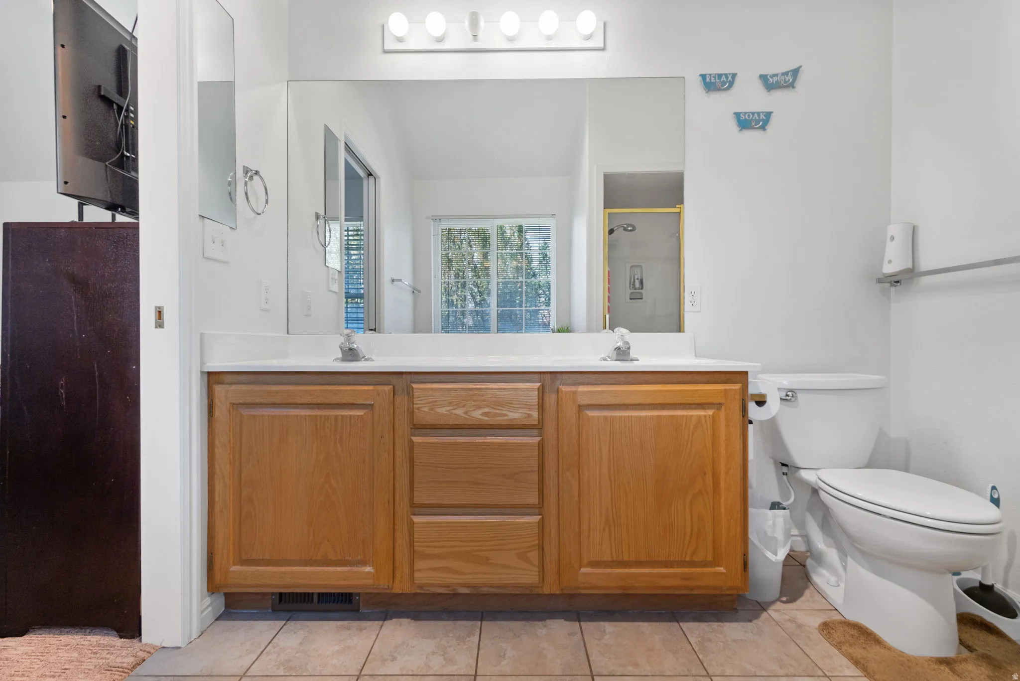 Bathroom with double vanity, a shower stall, and light tile patterned flooring