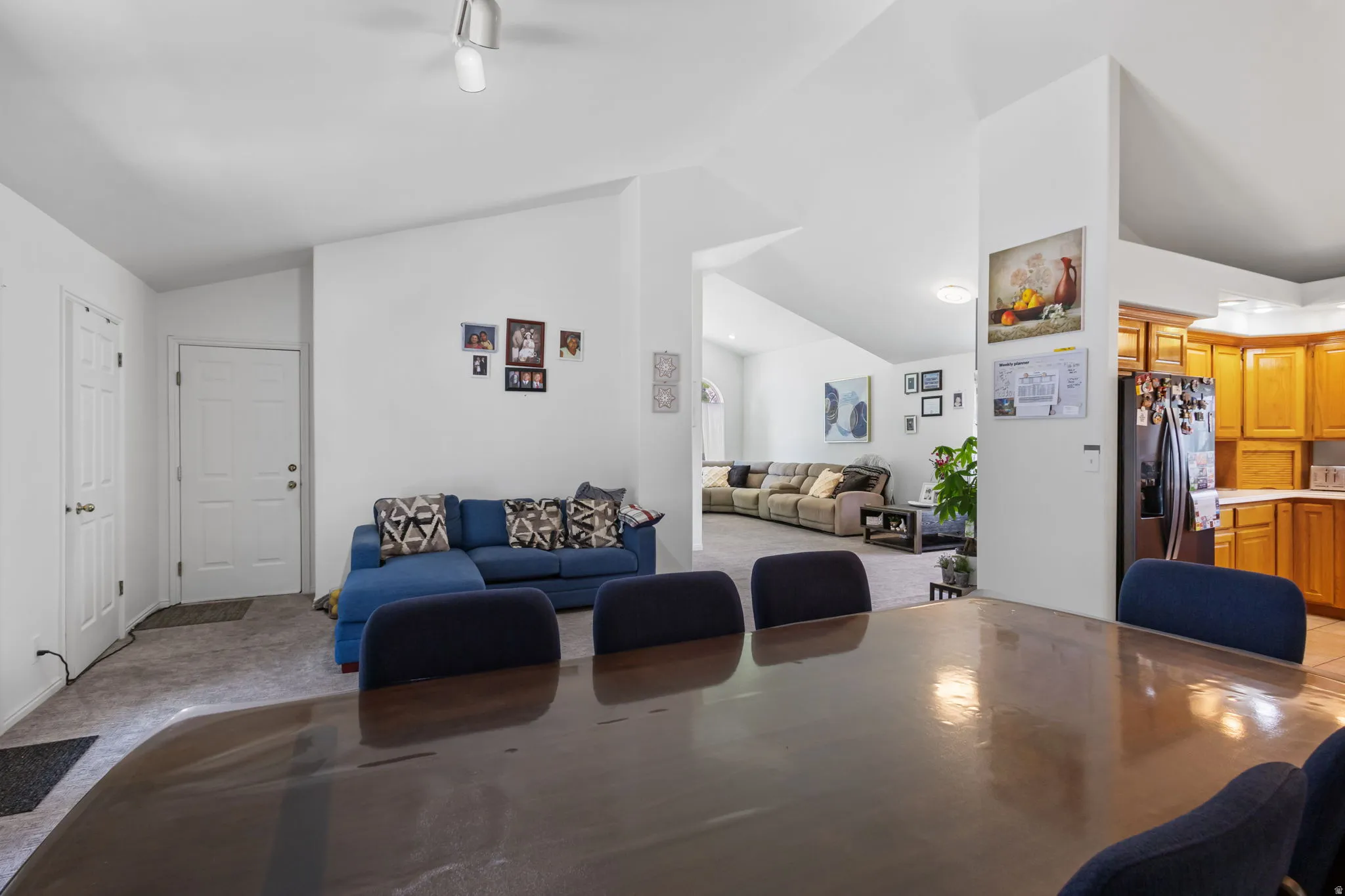 Dining area with light colored carpet and vaulted ceiling