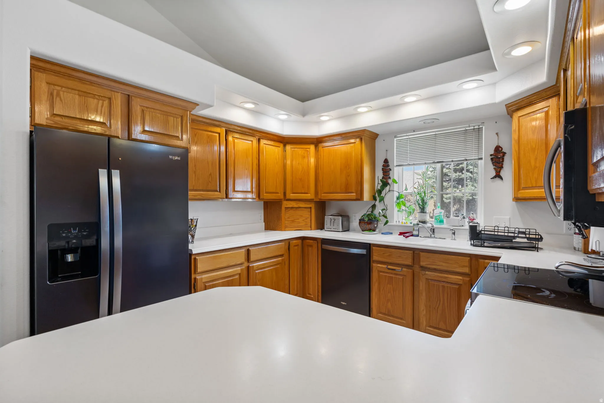 Kitchen with fridge with ice dispenser, wood finish cabinets, recessed lighting, light countertops, and black dishwasher