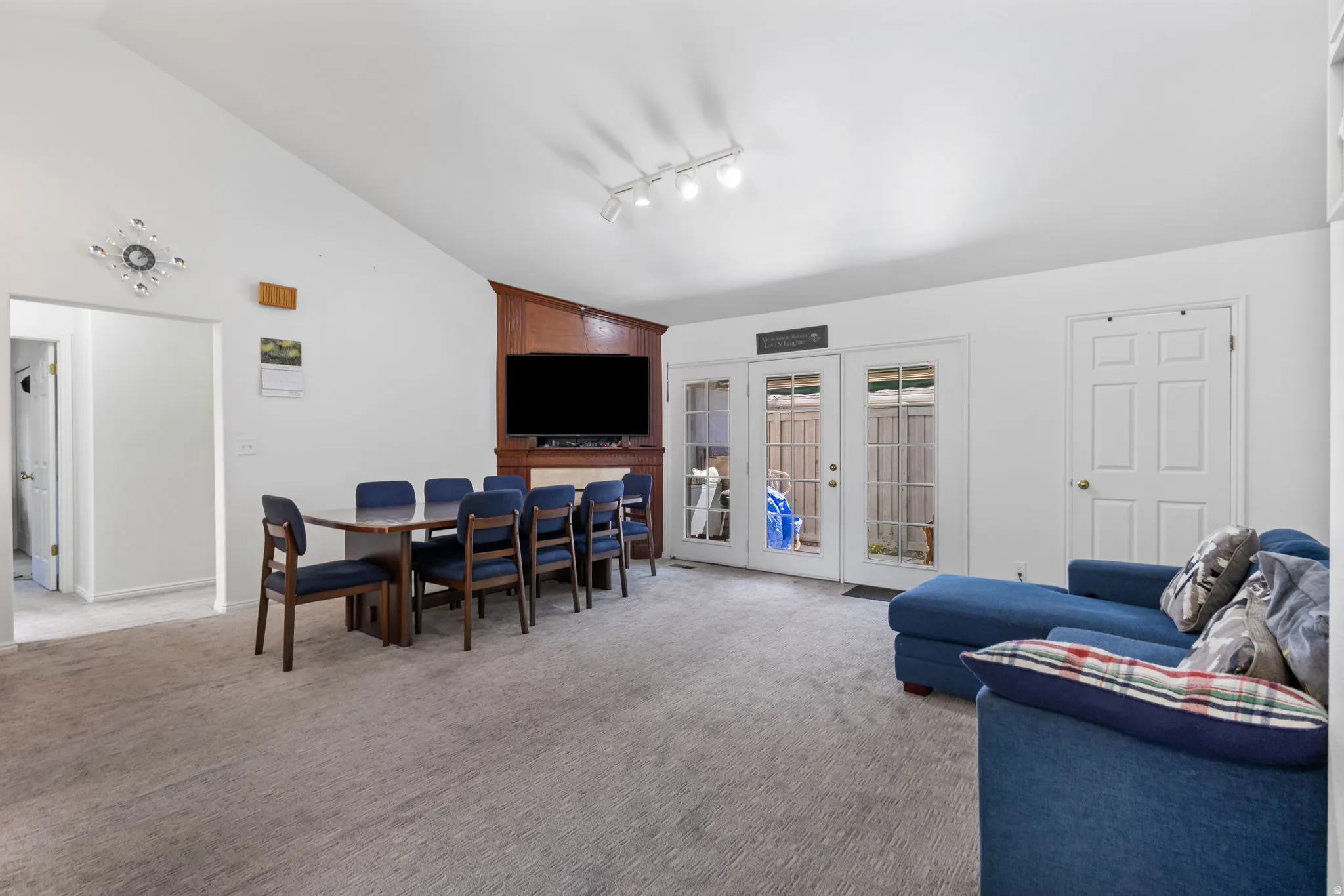 Living area featuring lofted ceiling, french doors, light carpet, and track lighting