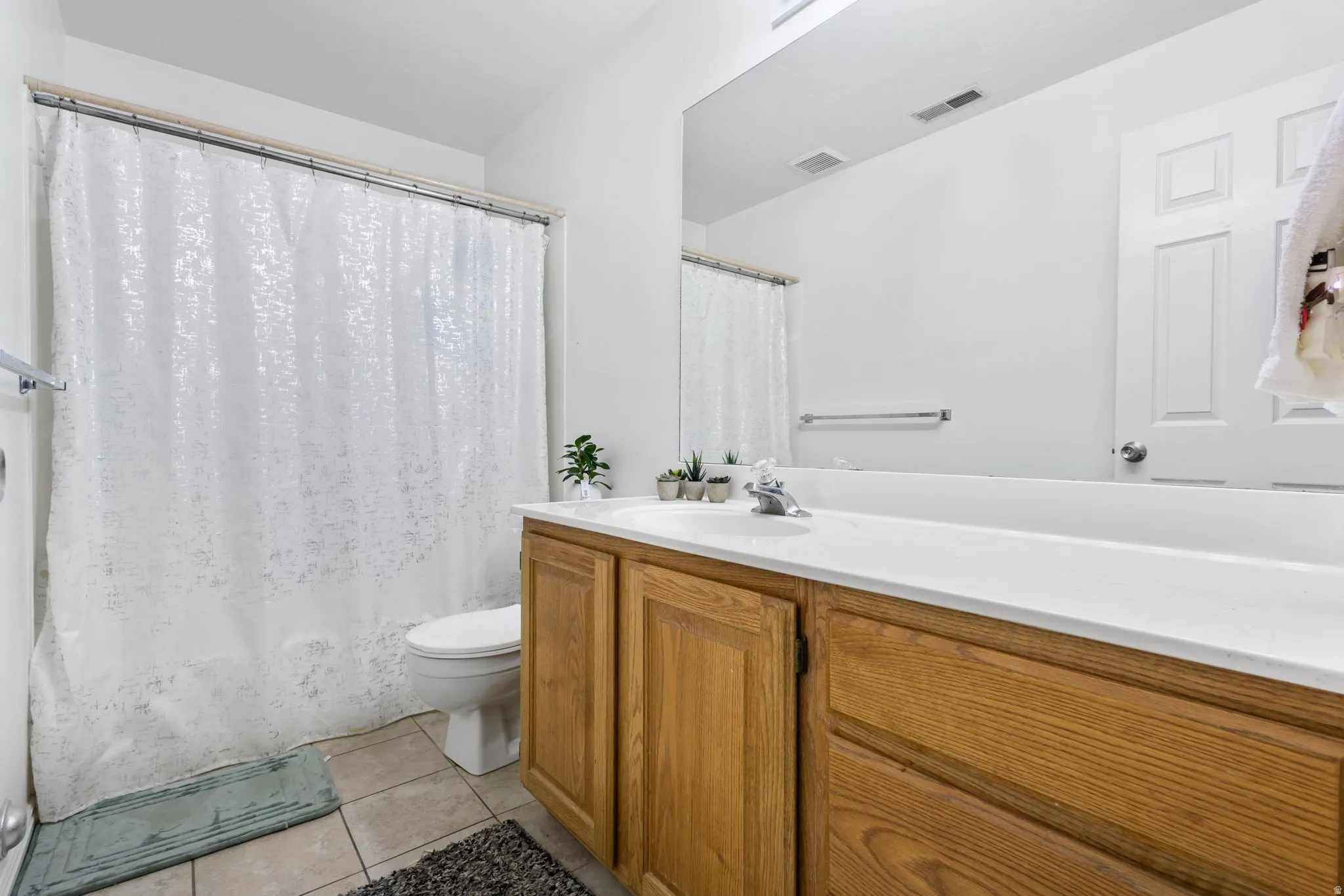 Bathroom with vanity, light tile patterned floors, and shower / bath combination with curtain