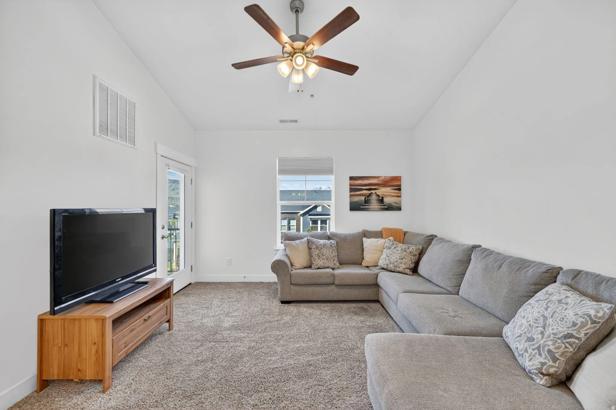Carpeted living area featuring vaulted ceiling and ceiling fan