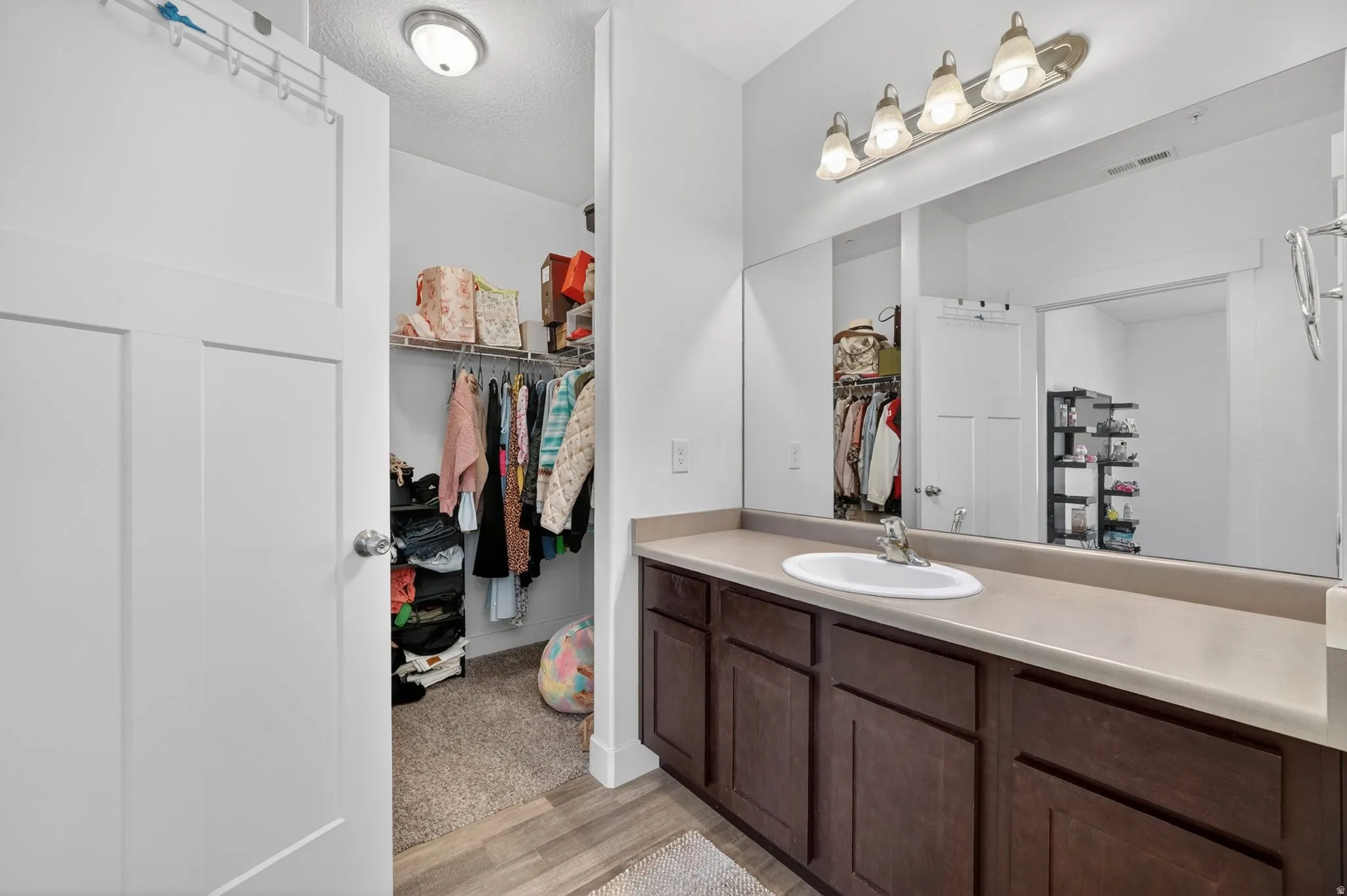 Bathroom with vanity, a walk in closet, and light wood-style floors