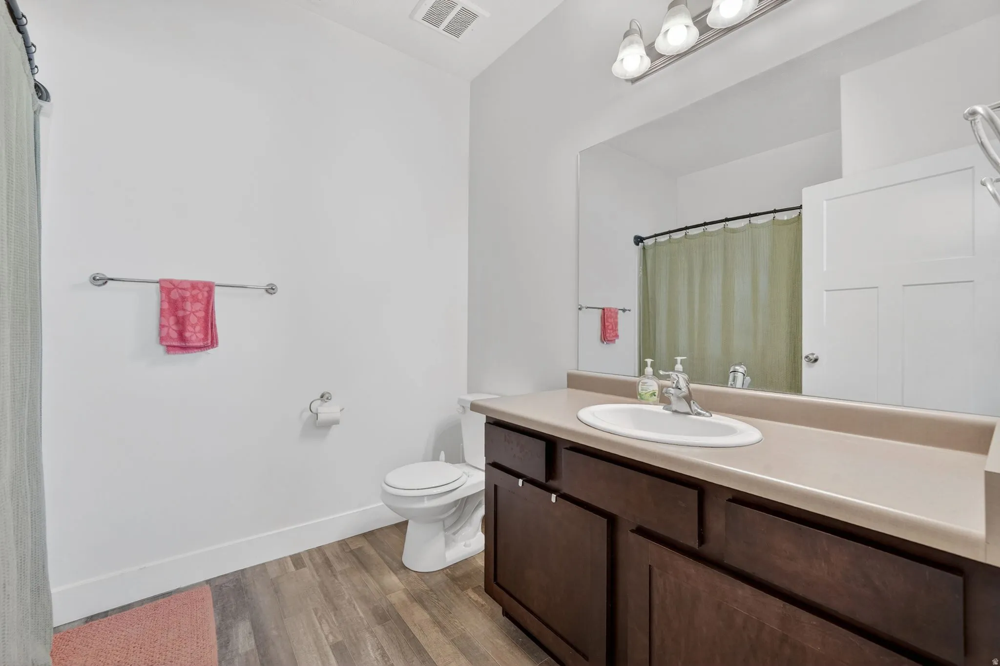 Bathroom featuring vanity, curtained shower, and dark wood-style flooring