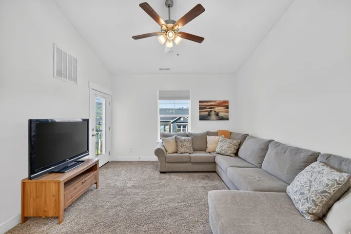 Carpeted living area featuring vaulted ceiling and ceiling fan