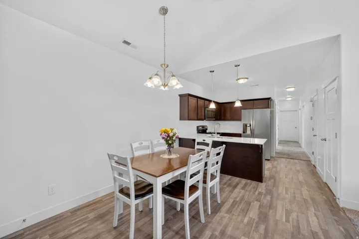 Dining space with vaulted ceiling, light wood finished floors, and suspended lighting