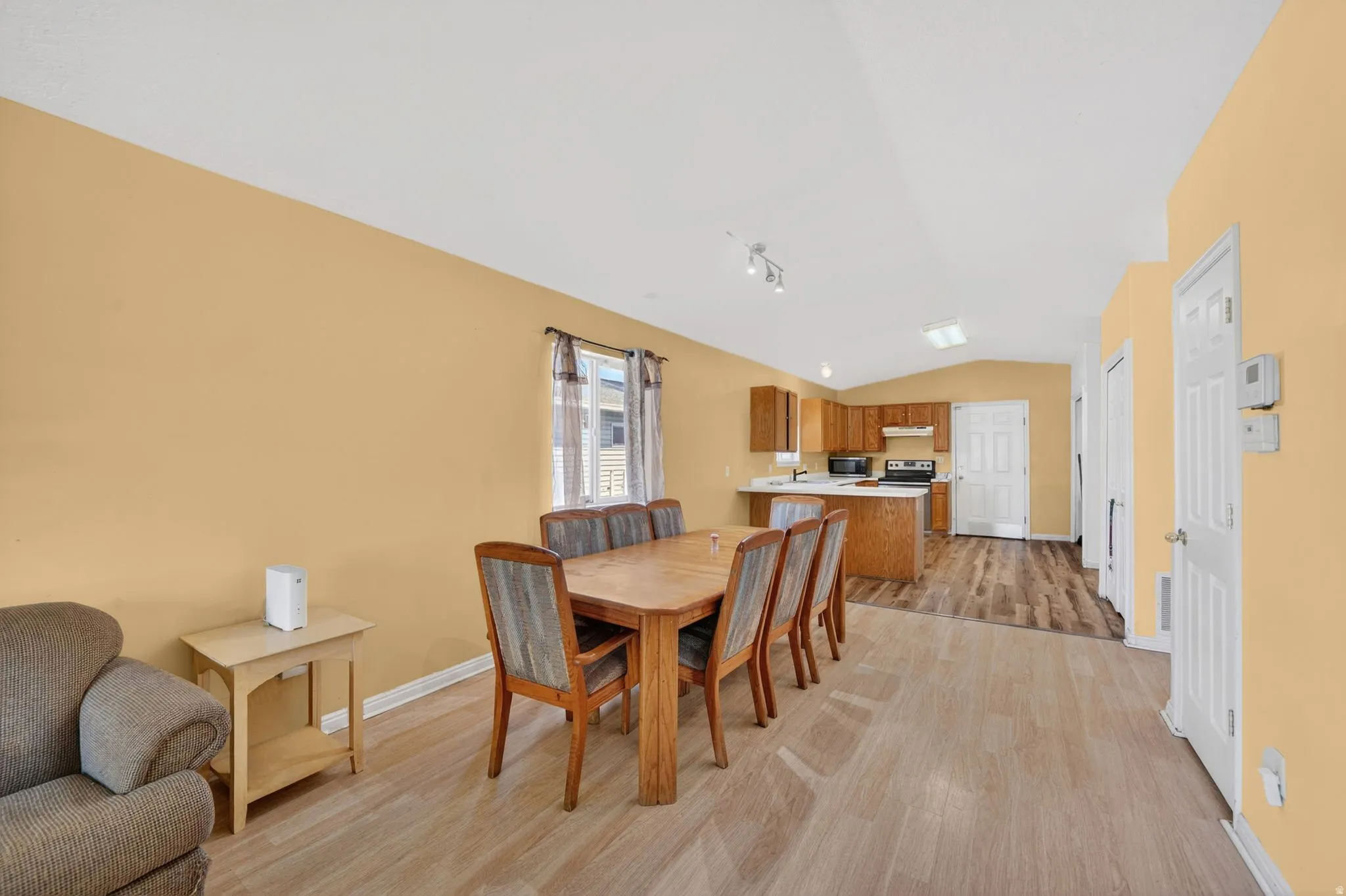 Dining area featuring lofted ceiling, light wood finished floors, and track lighting