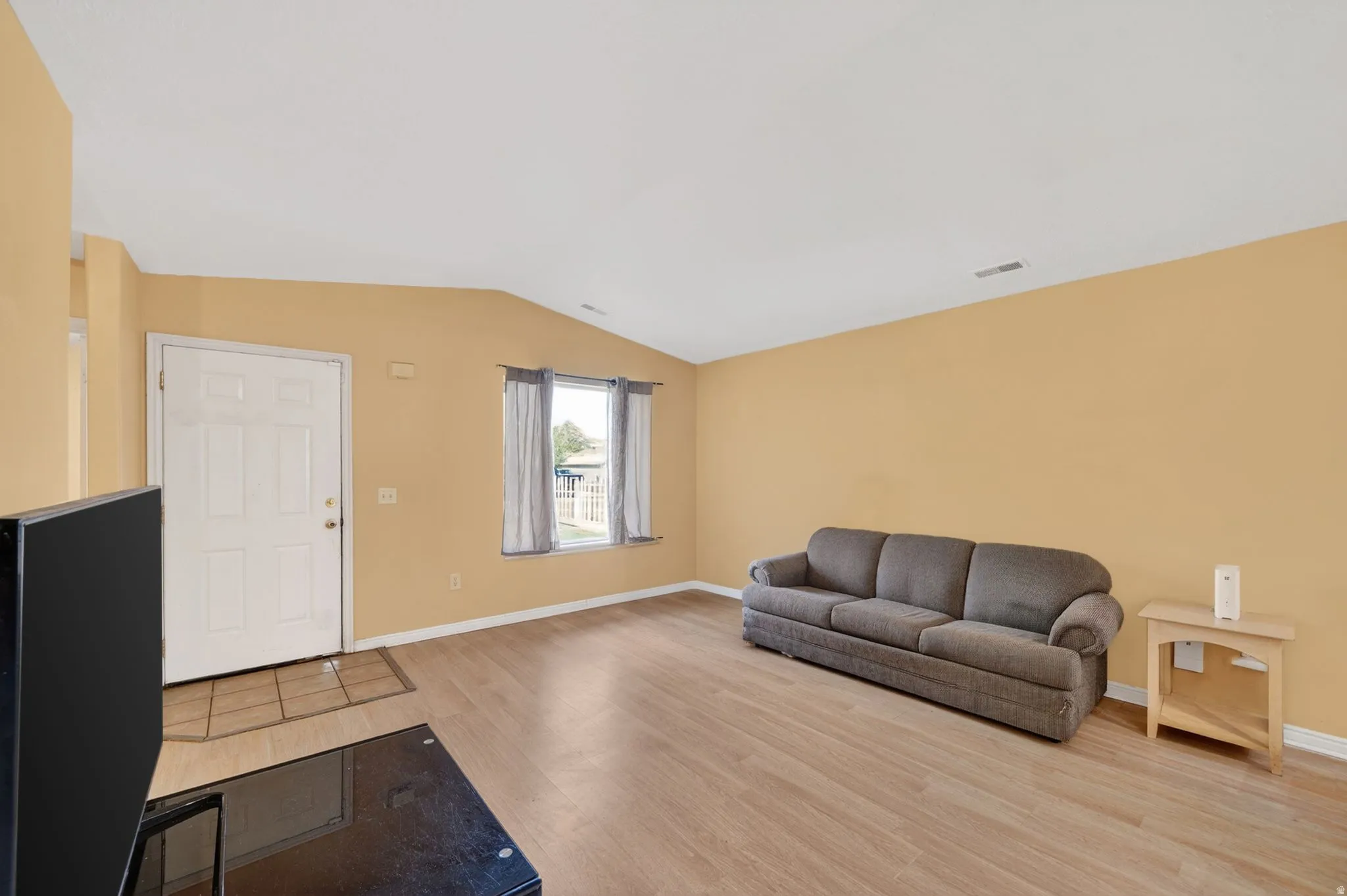 Living room featuring light wood-style flooring and vaulted ceiling