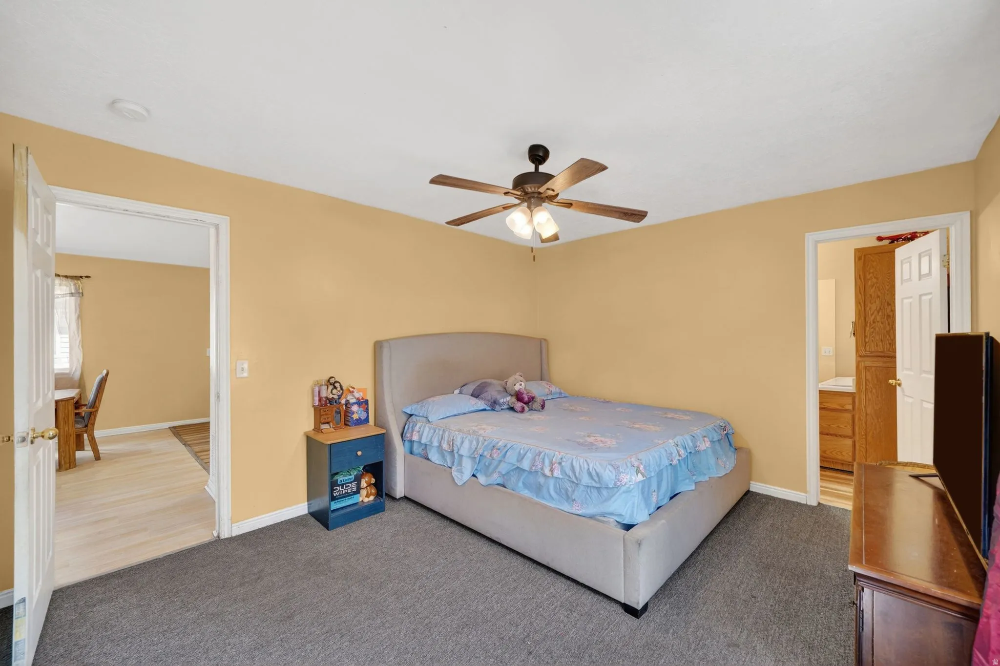 Carpeted bedroom featuring a ceiling fan and ensuite bath