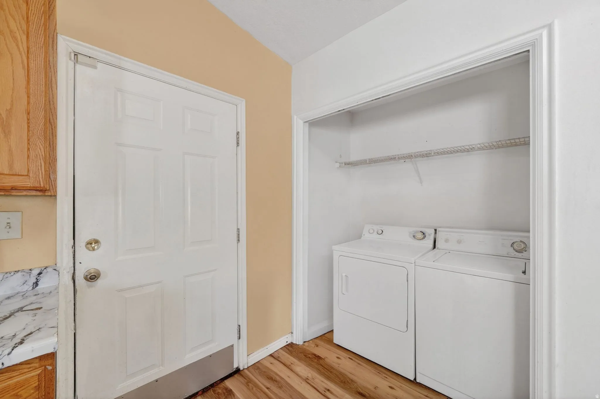 Laundry area featuring light wood-style floors and separate washer and dryer