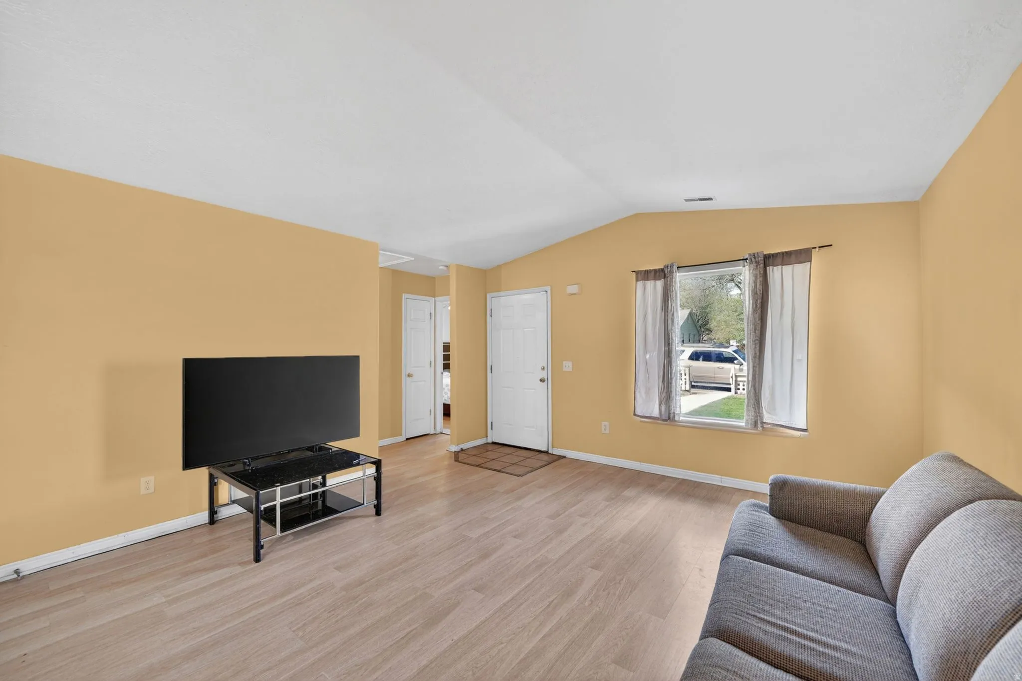 Living area featuring light wood-type flooring and vaulted ceiling