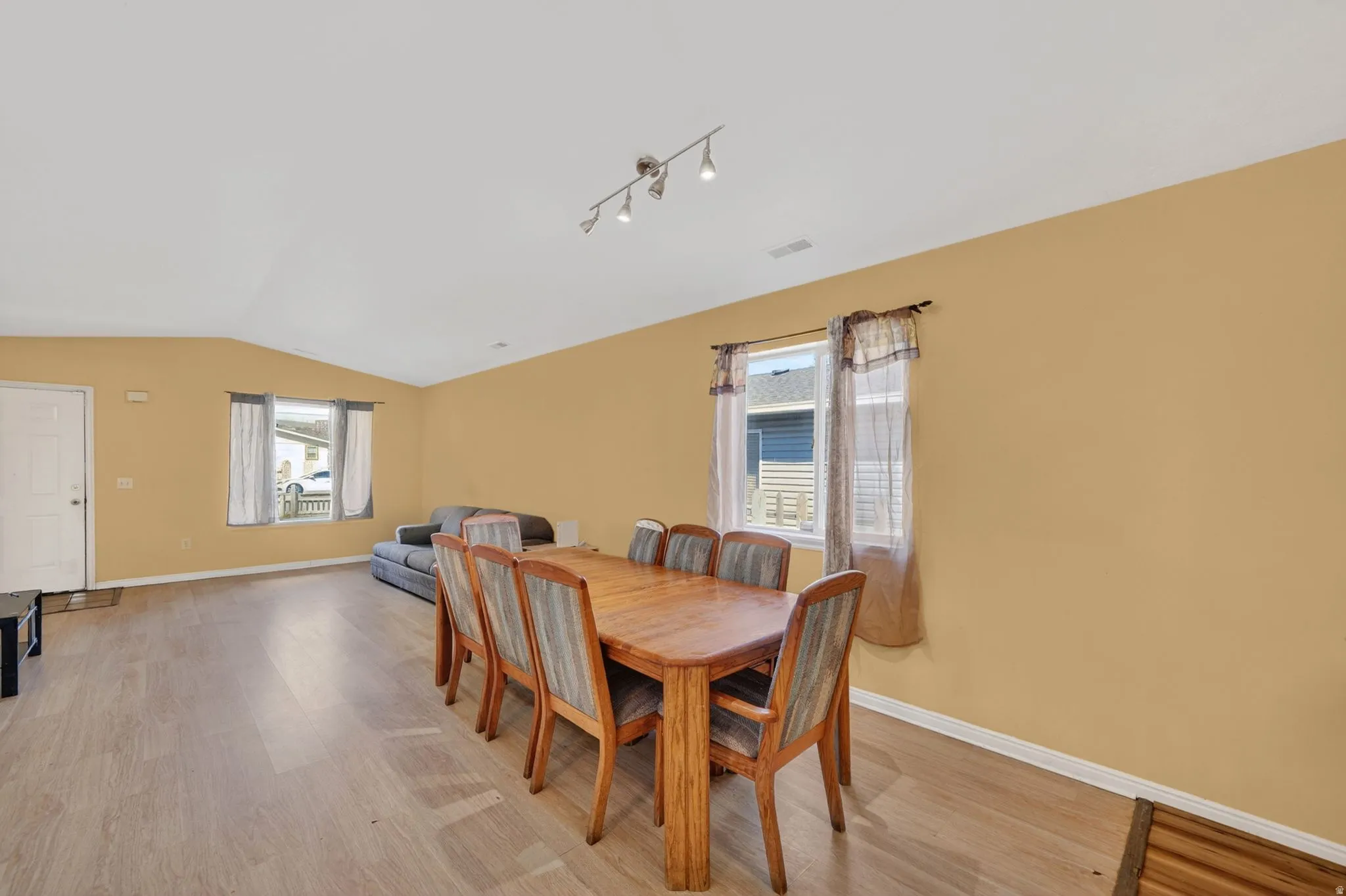 Dining area with healthy amount of natural light, light wood finished floors, and lofted ceiling
